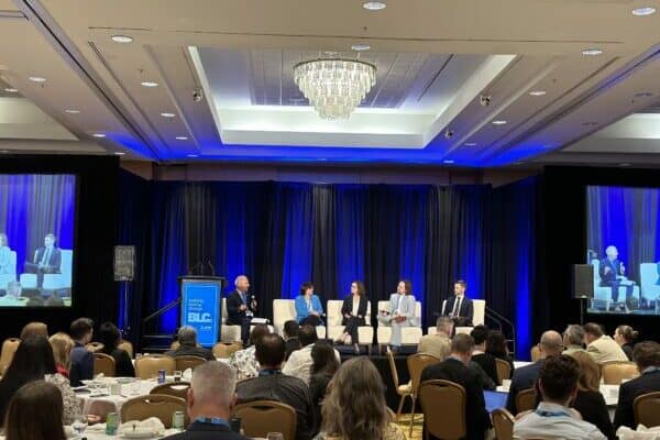 A group of people sit on stage of a panel.