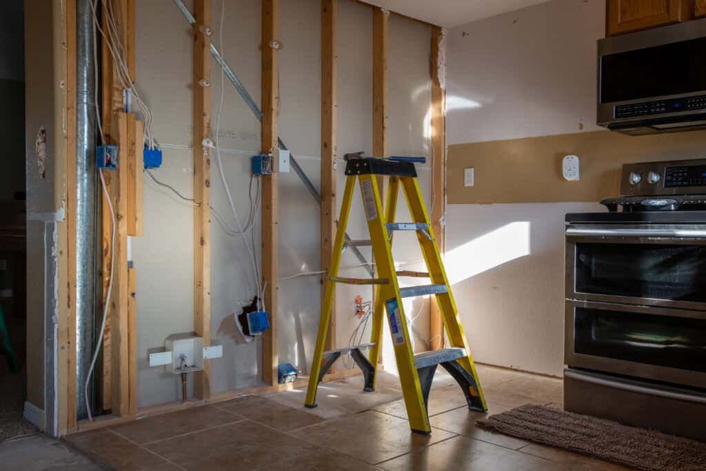 An unfinished kitchen with a ladder in the main hall.